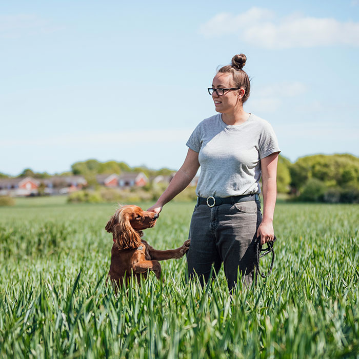 Woman in field with dog.